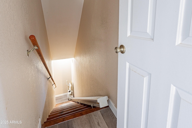 stairs featuring a textured wall and wood finished floors