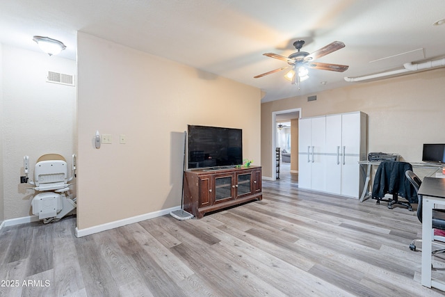 home office with light wood-style flooring, a ceiling fan, visible vents, and baseboards