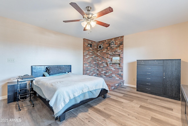 bedroom with light wood finished floors, a ceiling fan, and baseboards