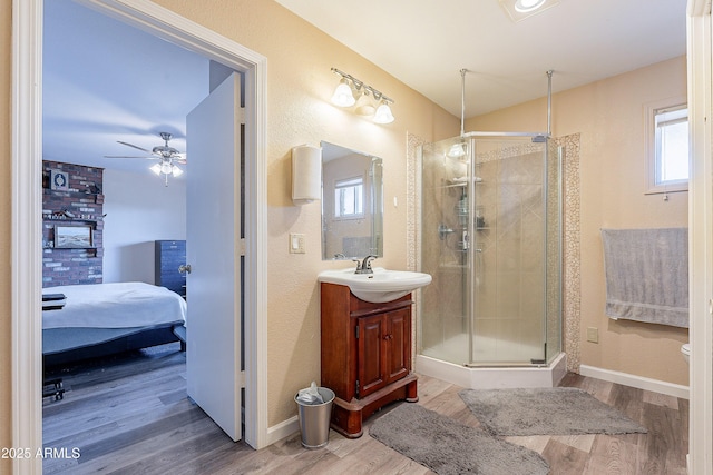 full bathroom featuring connected bathroom, a shower stall, vanity, wood finished floors, and baseboards