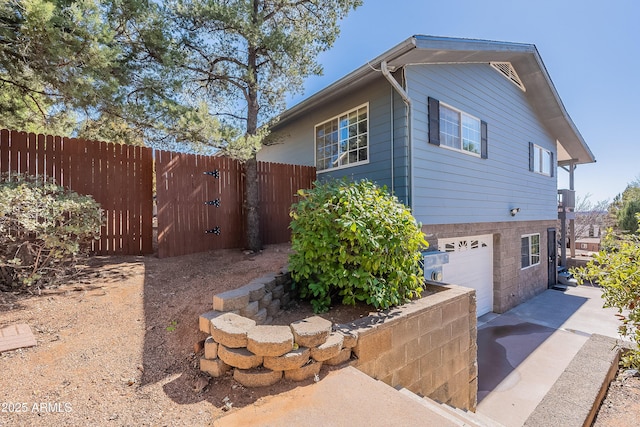 view of home's exterior with a garage, fence, and concrete driveway