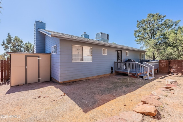 view of front of home with an outbuilding, fence, a chimney, and a storage unit