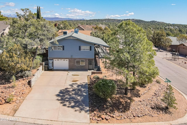 view of front of house featuring a garage, concrete driveway, stairway, fence, and brick siding