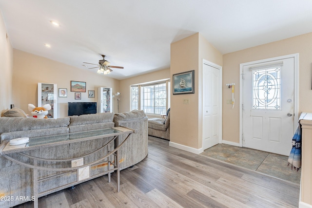 living area with lofted ceiling, ceiling fan, wood finished floors, and baseboards