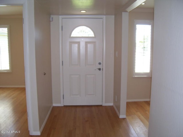 entryway featuring ornamental molding and light wood-type flooring