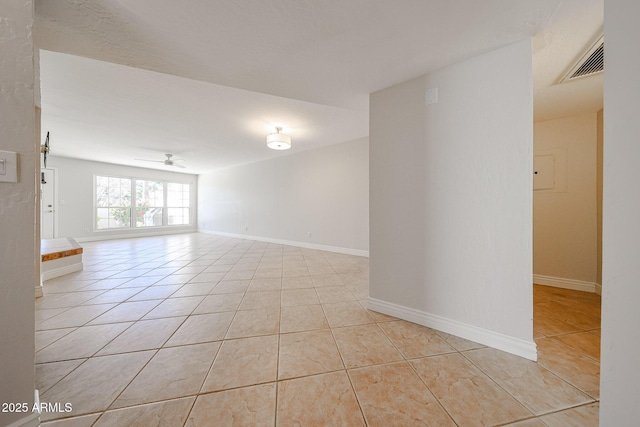 spare room featuring light tile patterned floors, ceiling fan, visible vents, and baseboards