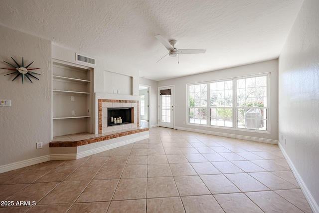 unfurnished living room with light tile patterned floors, baseboards, visible vents, built in features, and a textured ceiling