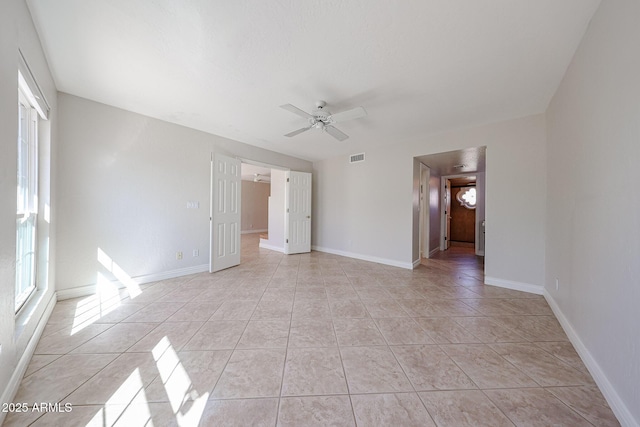 empty room with light tile patterned floors, baseboards, and a ceiling fan