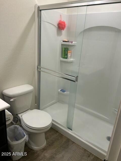 full bath with toilet, a shower stall, vanity, and wood finished floors