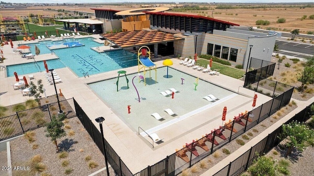 view of swimming pool featuring a water slide, a water play area, and fence
