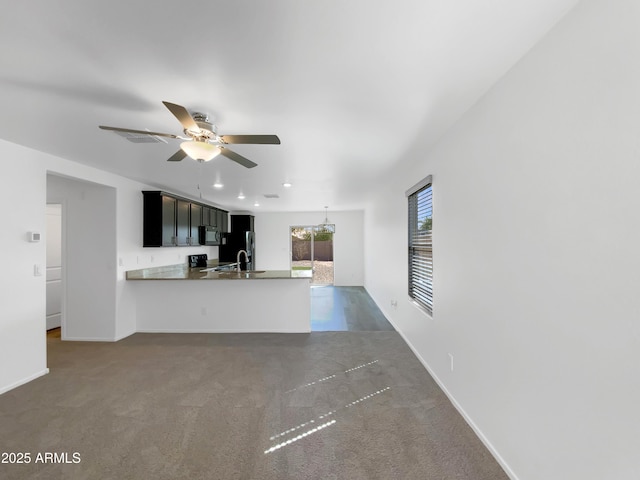 interior space with a sink, dark colored carpet, a peninsula, and ceiling fan