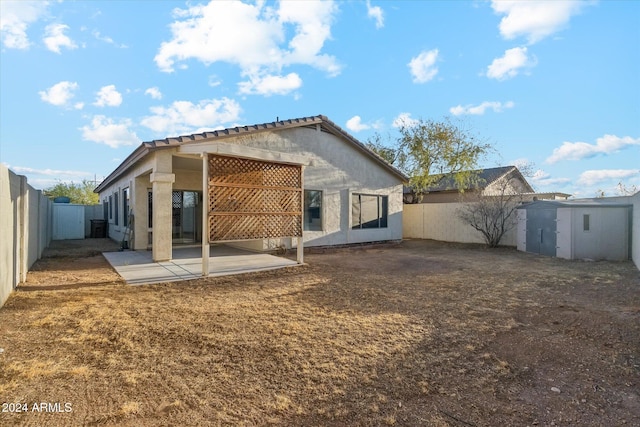 back of house with a storage unit and a patio area