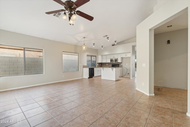 unfurnished living room featuring sink, vaulted ceiling, ceiling fan, and light tile patterned flooring