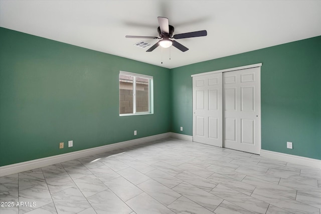 unfurnished bedroom featuring a closet, a ceiling fan, visible vents, marble finish floor, and baseboards