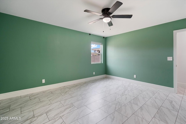 empty room with marble finish floor, ceiling fan, and baseboards