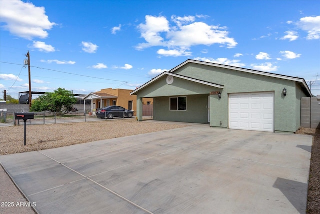 ranch-style home featuring an attached garage, concrete driveway, stucco siding, and fence
