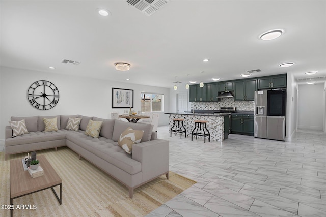 living area with marble finish floor, visible vents, and recessed lighting