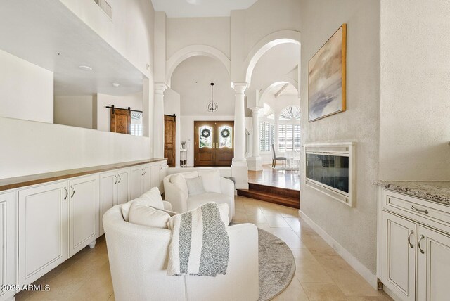 10205 E Corrine Dr, Scottsdale, AZ 85260 - living area featuring ornate columns, light tile patterned floors, a high ceiling, baseboards, and arched walkways