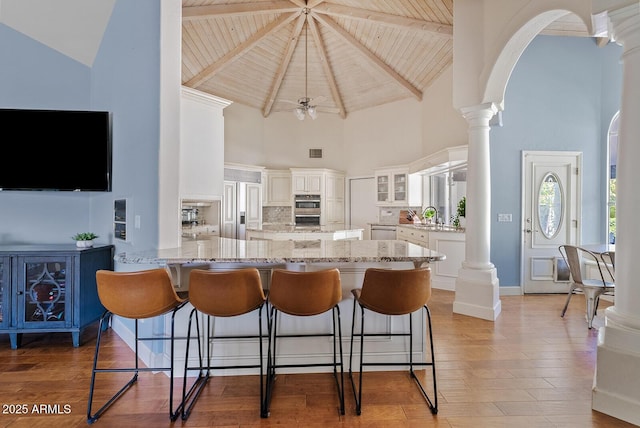 10205 E Corrine Dr, Scottsdale, AZ 85260 - kitchen with high vaulted ceiling, ornate columns, a peninsula, double oven, and glass insert cabinets