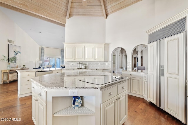 10205 E Corrine Dr, Scottsdale, AZ 85260 - kitchen with paneled built in fridge, arched walkways, high vaulted ceiling, a peninsula, and light stone counters