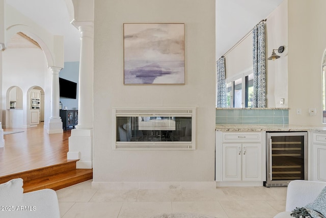 10205 E Corrine Dr, Scottsdale, AZ 85260 - living room featuring wine cooler, decorative columns, arched walkways, a towering ceiling, and light tile patterned flooring