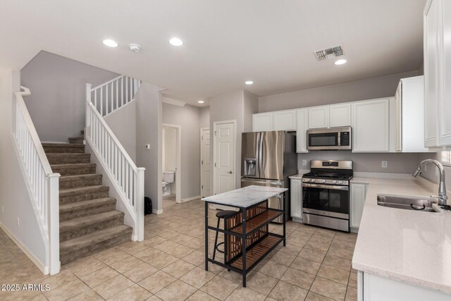 5812 W Illini St, Phoenix, AZ 85043 - kitchen featuring appliances with stainless steel finishes, white cabinets, recessed lighting, light tile patterned flooring, and light stone countertops