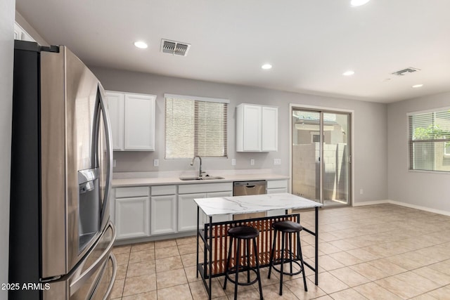 5812 W Illini St, Phoenix, AZ 85043 - kitchen featuring appliances with stainless steel finishes, white cabinetry, light tile patterned floors, recessed lighting, and a kitchen breakfast bar