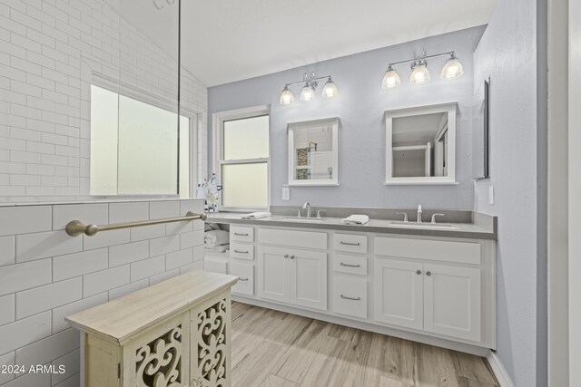 bathroom with wood-type flooring, vanity, tile walls, and lofted ceiling