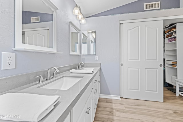 bathroom featuring wood-type flooring, vaulted ceiling, and vanity