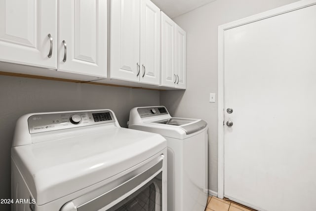 washroom with cabinets, light tile patterned floors, and washer and clothes dryer