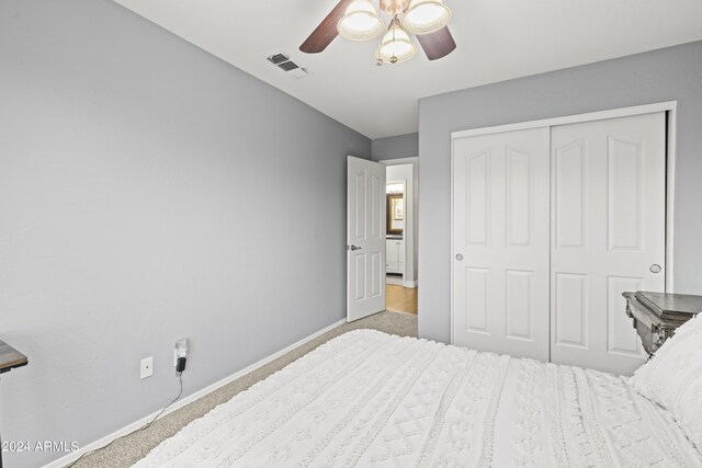 carpeted bedroom featuring ceiling fan and a closet