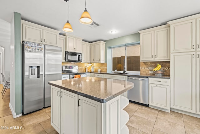 kitchen featuring sink, a kitchen island, decorative light fixtures, stainless steel appliances, and decorative backsplash