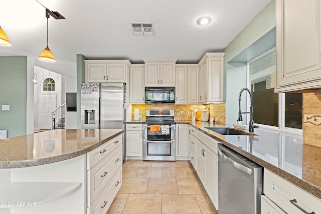 kitchen featuring light tile patterned flooring, hanging light fixtures, sink, appliances with stainless steel finishes, and decorative backsplash