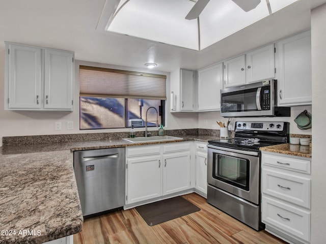 kitchen with light wood-type flooring, sink, stainless steel appliances, and white cabinets