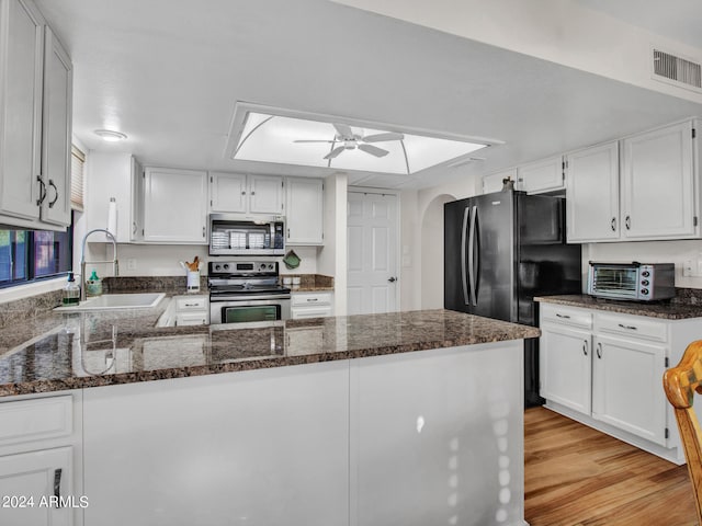 kitchen with appliances with stainless steel finishes, light wood-type flooring, kitchen peninsula, and white cabinetry