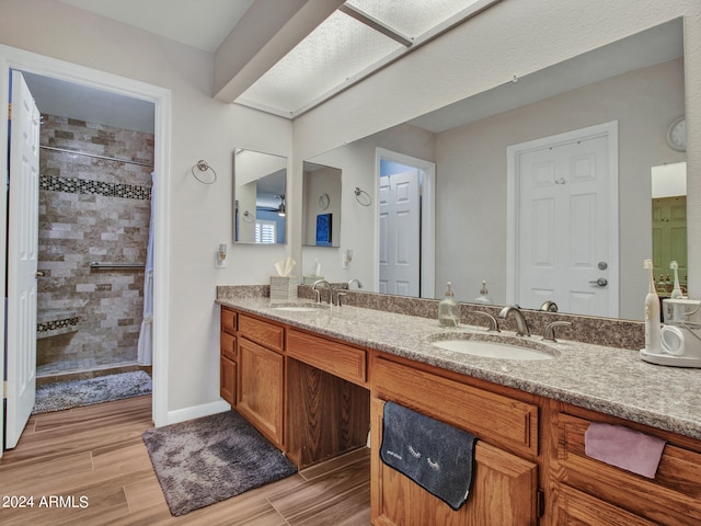 bathroom featuring tiled shower, vanity, and wood-type flooring