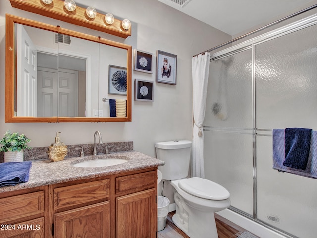 bathroom with walk in shower, vanity, hardwood / wood-style floors, and toilet