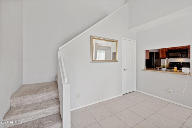 stairway with tile patterned floors and a high ceiling