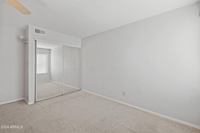 unfurnished bedroom with ceiling fan, a closet, and light colored carpet