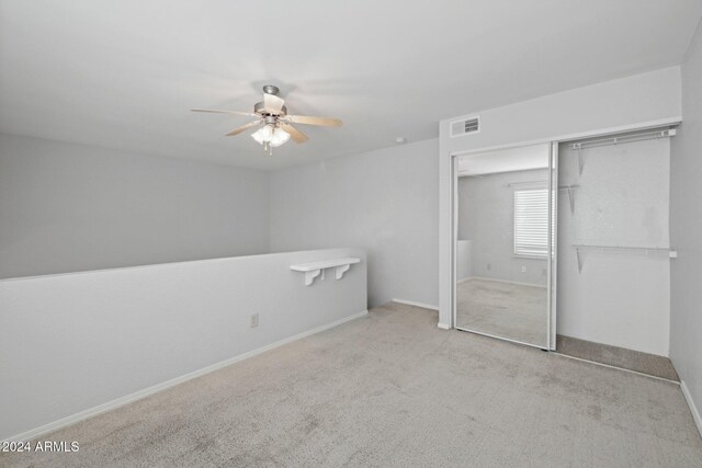 unfurnished bedroom featuring ceiling fan, light colored carpet, and a closet