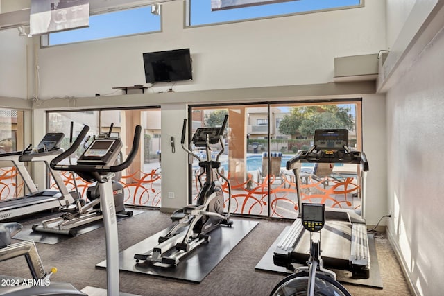 workout area featuring a wall mounted AC and a high ceiling