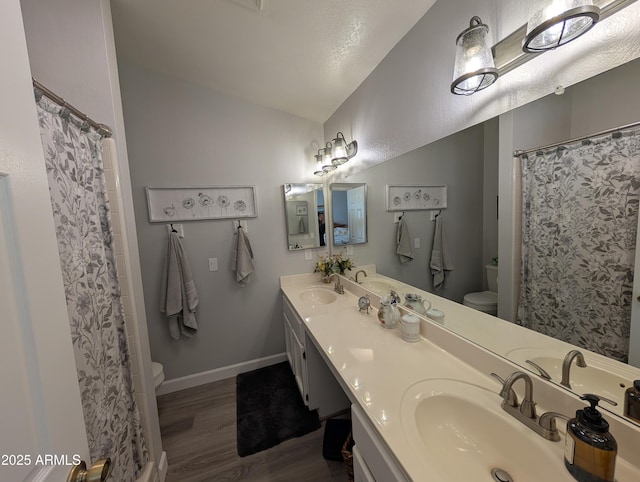 bathroom with vaulted ceiling, toilet, wood finished floors, and a sink