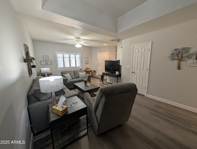 living room featuring ceiling fan, baseboards, dark wood-style flooring, and a textured ceiling