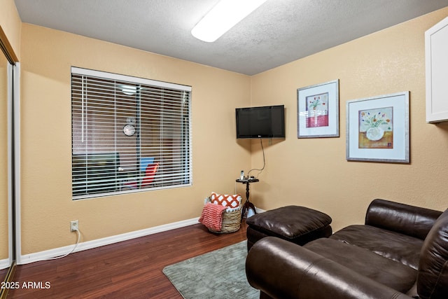 living area featuring wood finished floors, baseboards, and a textured ceiling