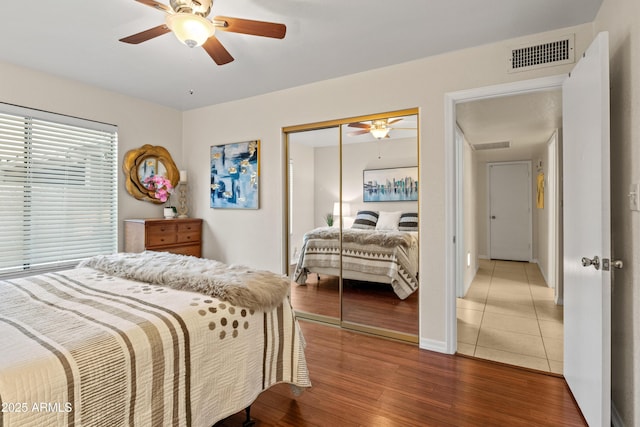 bedroom with a closet, visible vents, a ceiling fan, and wood finished floors