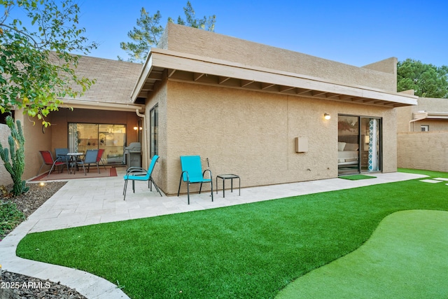 rear view of property featuring stucco siding, fence, and a patio area