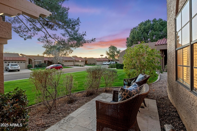 patio terrace at dusk featuring a yard and a residential view