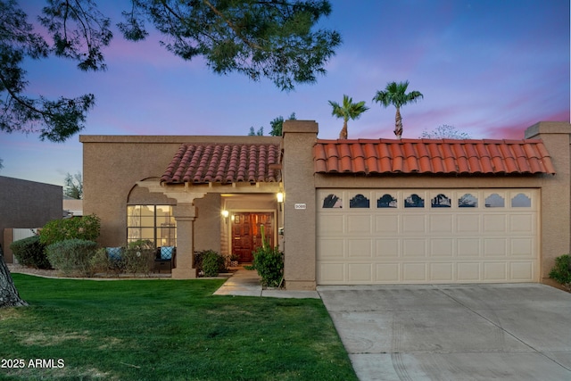 view of front of home with driveway, an attached garage, stucco siding, a front lawn, and a tiled roof