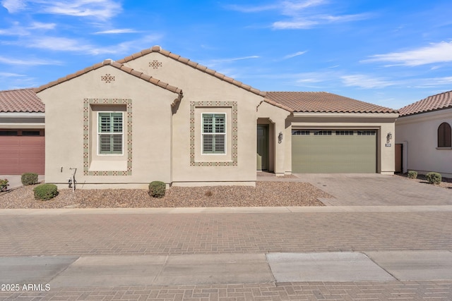 mediterranean / spanish-style house featuring a garage, a tile roof, decorative driveway, and stucco siding