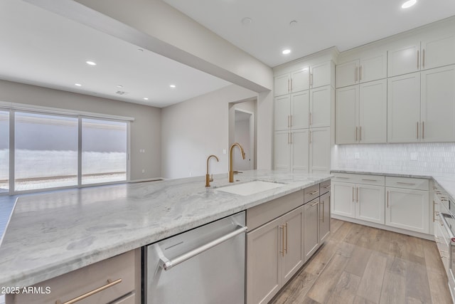 kitchen with light stone counters, tasteful backsplash, light wood-style floors, a sink, and dishwasher